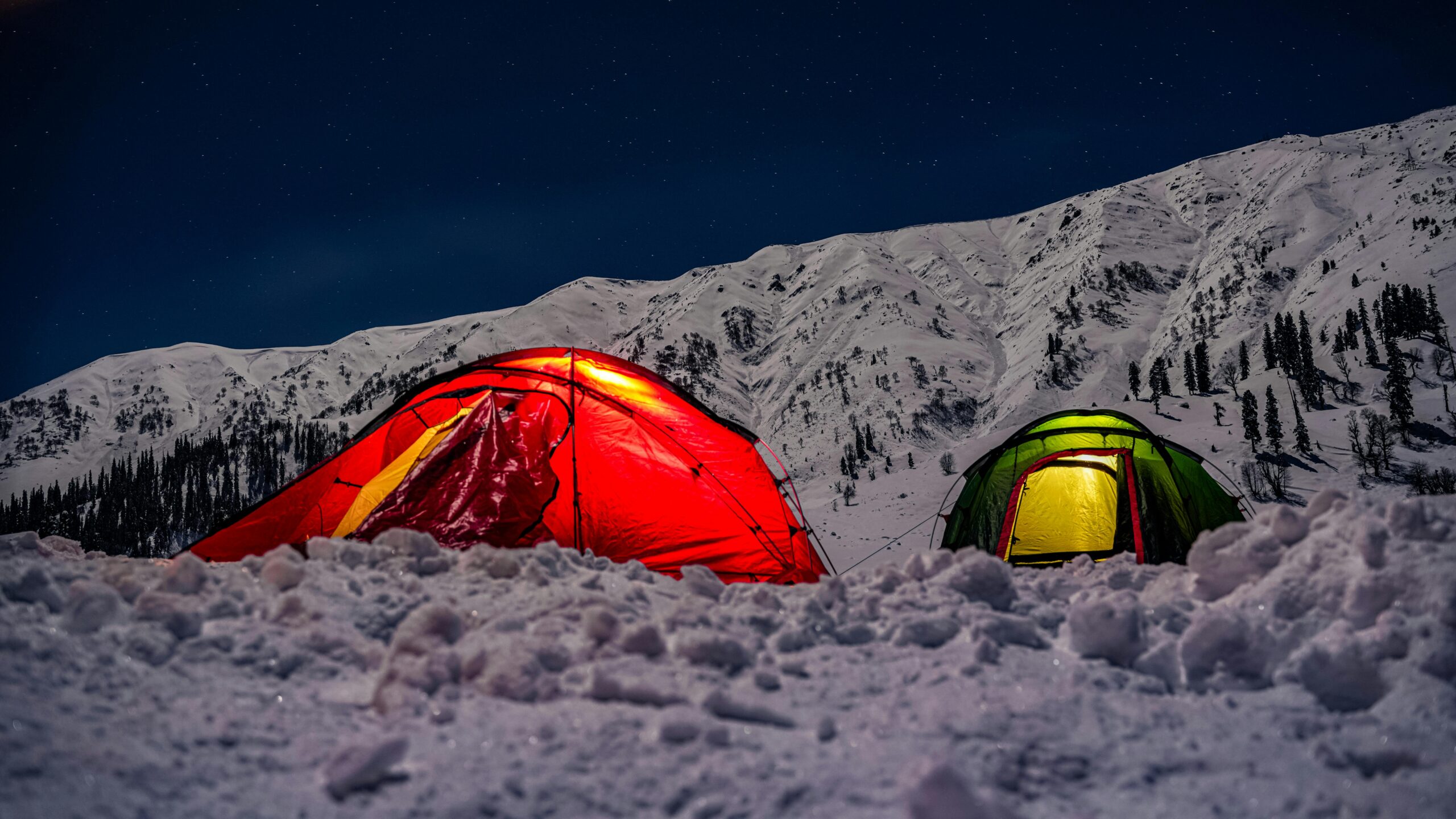 Two Tents with Lights Inside on the top of a Snowy Mountain